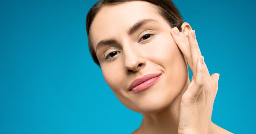 Happy woman with soft skin touching her face, portraying natural beauty.